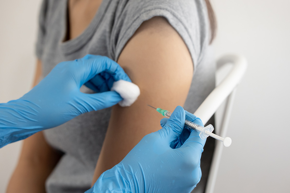 The arm of a woman receiving a vaccination is shown.