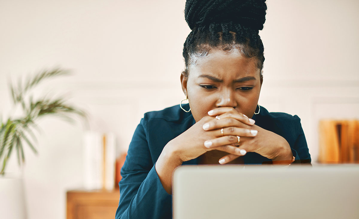 A woman looks at her computer with a concerned expression.